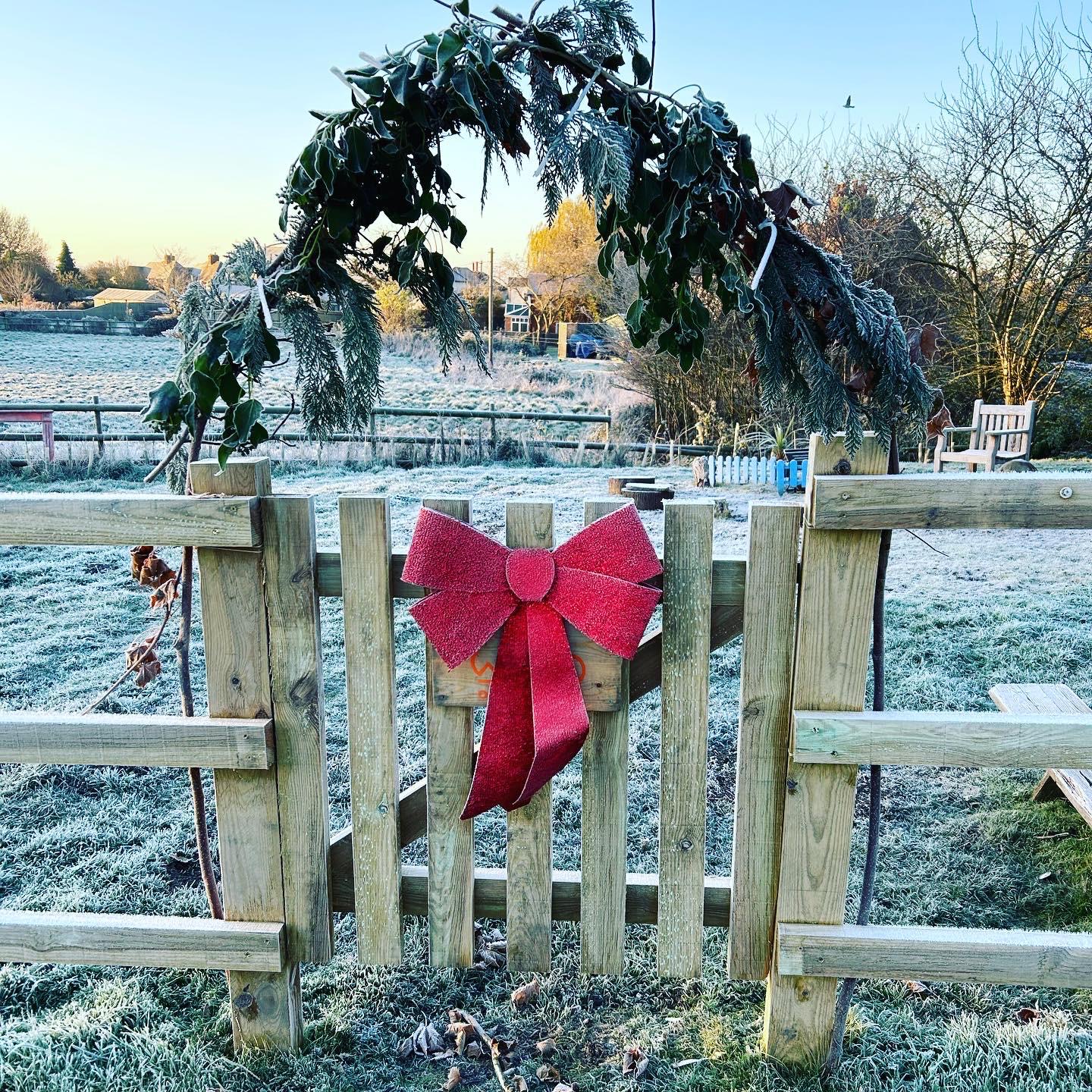 The WildOnes gate with a red bow and foliage arch on a frosty morning