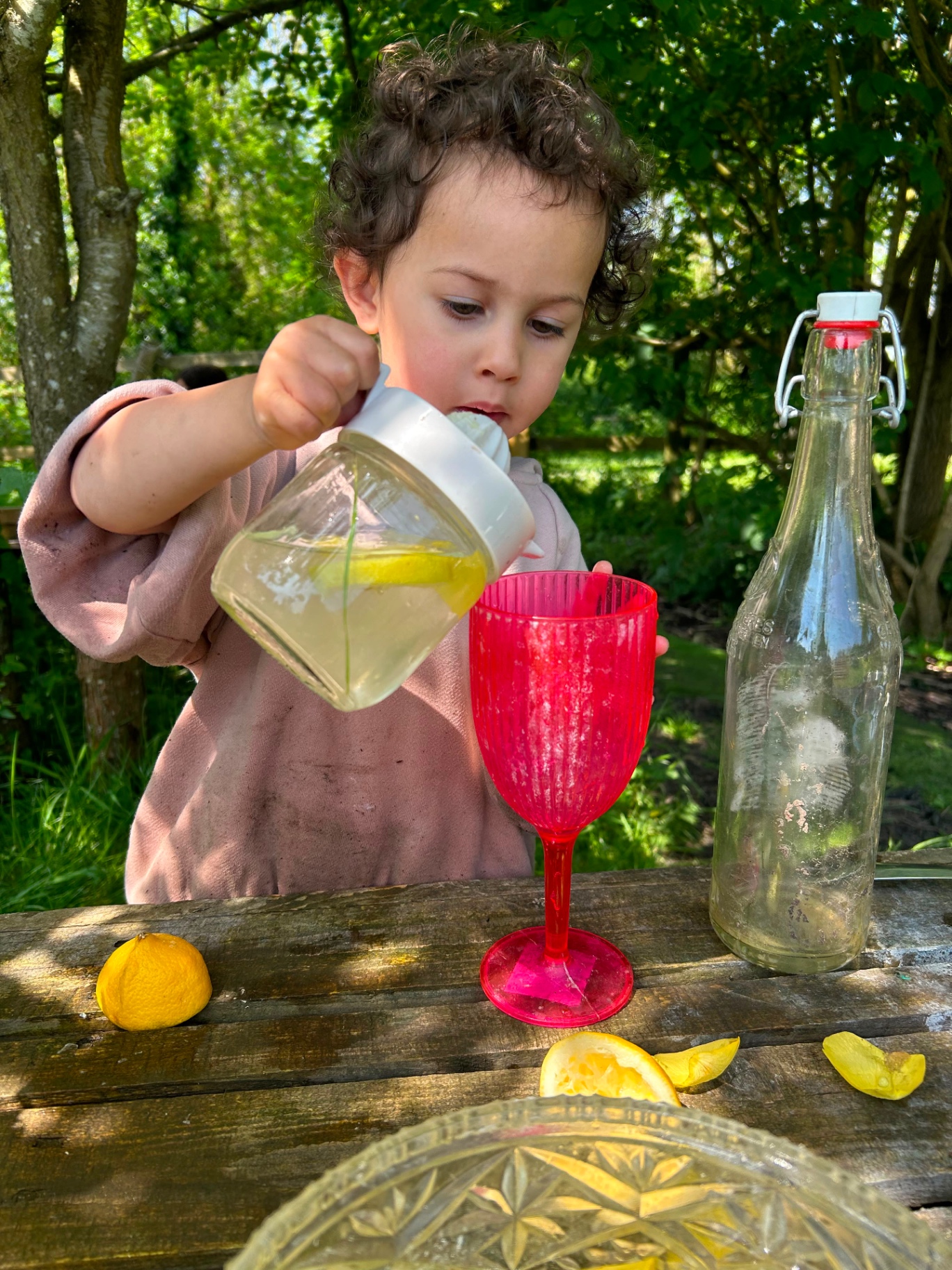 A child pouring lemonade into a cup outdoors